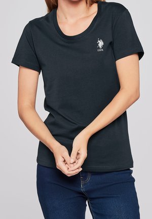 Bawełniany T-shirt w ciemnym granacie z okrągłym dekoltem. Na piersi znajduje się biały haftowany logotyp. Krótkie rękawy i luźny krój.