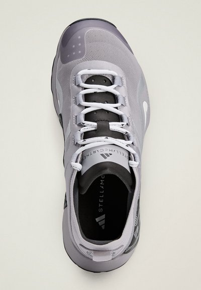 Gray athletic shoe with mesh upper, white laces, black accents, and a textured heel. Features logo on tongue and pattern on the side.