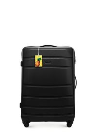 Black hard-shell suitcase with textured surface, horizontal ridges, a top handle, and four wheels. Includes a yellow pineapple tag.