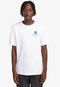 Camiseta blanca de algodón con mangas cortas, cuello redondo, que presenta un texto gráfico azul "SKATEBOARD COMPANY" y un logo en el área del lado izquierdo del pecho.