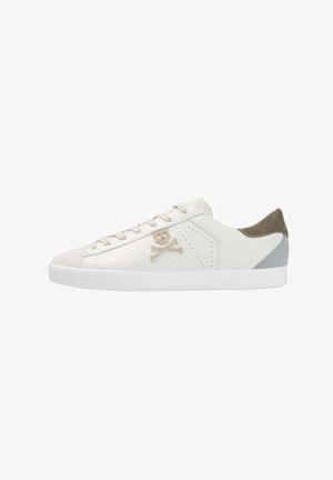 Zapatilla blanca de caña baja con logo de calavera y huesos cruzados en beige, detalles en el talón en gris y oliva y suela de goma blanca.