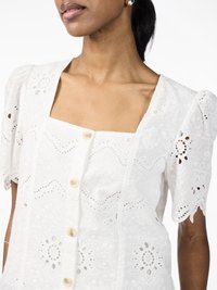 White embroidered blouse featuring a square neckline, short puff sleeves, and button closures, with floral patterns and eyelet detailing.