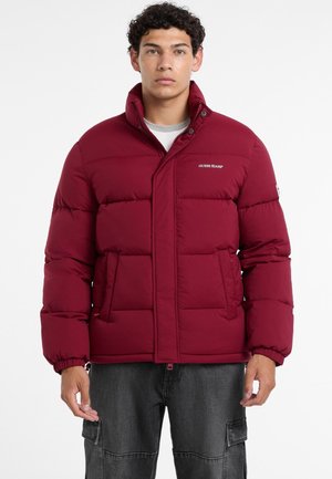 Chaqueta acolchada burdeos con cuello alto, con acolchado horizontal, bolsillos laterales y un logo en el pecho. Textura de tela suave.