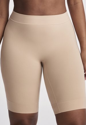 High-waist seamless beige biker shorts worn by a person, extending to mid-thigh with a smooth, fitted appearance.