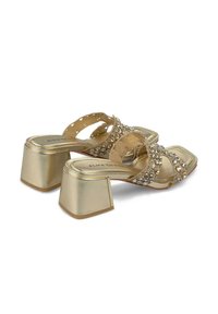 Gouden hoge haksandalen met een vierkante neus, versierd met decoratieve stenen, en een chunky hak voor stabiliteit.