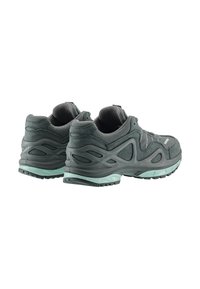 Scarpe sportive grigie con tomaia testurizzata, suole imbottite e un accento verde menta lungo il plantare. Suola con trazione multidirezionale.