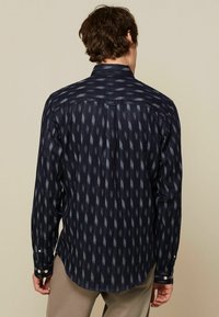 Marineblauwe overhemd met knopen en een geometrisch patroon, lange mouwen en een gespreid kraag. Voorzien van knoopmanchetten en een gebogen zoom.
