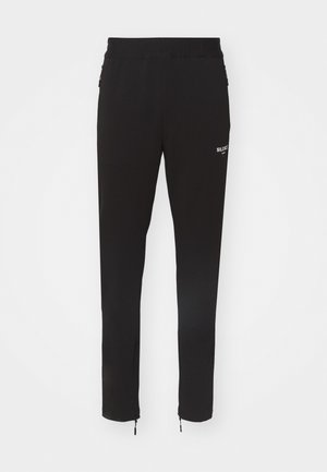 Črne športne hlače s slim fit krojem, elastičnim pasom in z zadrgo pri gležnjih. Ponuja belo logotipno podrobnost na boku. Gladek tekstil.
