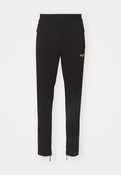 Svarta träningsbyxor med slim fit, elastisk midjeresår och dragkedjor vid anklarna. Har en vit logotypdetalj på höften. Slät tygtextur.