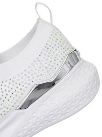 Sneaker slip-on bianca con strass iridescenti, dettaglio metallico argento e suola spessa e strutturata con motivo geometrico.
