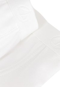 Biancheria intima in cotone bianco con una cintura morbida che presenta un logo impresso. La vista ravvicinata mette in evidenza la cucitura e la texture liscia.
