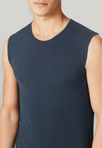 Canottiera senza maniche di colore blu navy con scollatura rotonda, realizzata in tessuto di cotone liscio. Caratterizzata da un design aderente e cuciture minime.