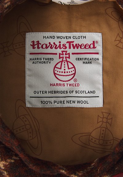 Harris Tweed label features red and black text on a white fabric background, stating "100% Pure New Wool" and "Hand Woven Cloth." Brown interior with patterns.