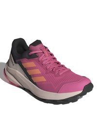 Zapatilla de trail running rosa con parte superior de malla, acentos en negro y naranja, cuello acolchado y suela de goma texturizada para tracción.