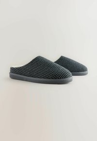 Gray knitted slippers with a textured surface, a cushioned interior, and a flat rubber sole. Simplistic and ergonomic design.