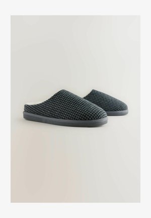 Szare, dzianinowe kapcie o teksturowanej powierzchni, z wyściełanym wnętrzem i płaską gumową podeszwą. Prosty i ergonomiczny design.