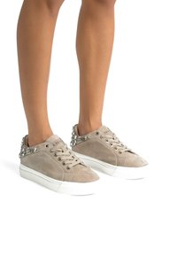 Sneaker in suede beige con profilo basso, punta rotonda e decorazione sul retro. Caratterizzate da lacci abbinati e suola in gomma bianca.