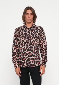 Leopard print shirt in pink and black, featuring a button-up design, long sleeves, and a smooth fabric texture. Worn with black pants.