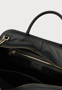 Μαύρη δερμάτινη τσάντα με χρυστό φερμουάρ, μονό επάνω χερούλι και εσωτερική τσέπη με φερμουάρ με ετικέτα "BOSS".