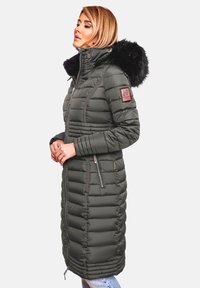 Puffer coat in dark green, featuring a faux fur hood, side zipper pockets, and horizontal quilted design with a logo patch on the sleeve.
