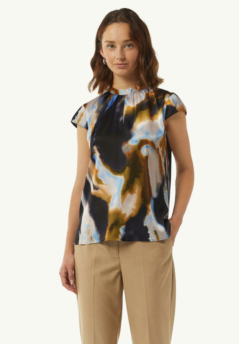 Mehrfarbige Bluse aus fließendem Stoff mit Rundhalsausschnitt, kurzen Ärmeln und abstrakten Mustern in Blau-, Braun- und Schwarztönen.