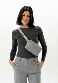 Šedá křížová taška s hladkým povrchem a obdélníkovým tvarem, vybavená popruhem a jednoduchým logem na přední straně.