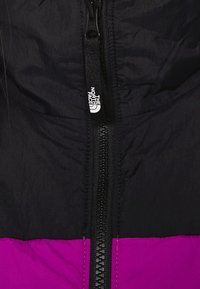 Černá a fialová zateplená bunda s centrálním zipem. Obsahuje texturovanou látku a značkovou večku na zip od The North Face.