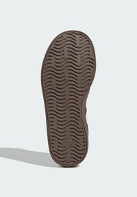 Brązowa gumowa podeszwa buta z falistym wzorem bieżnika i wytłoczonym logo. Charakteryzuje się gładką, matową fakturą i profilowanym kształtem.