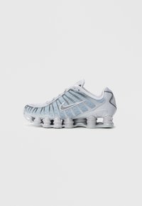 Αθλητικά παπούτσια ανοιχτού μπλε χρώματος με επάνω μέρος από δίχτυ, λαστιχένια σόλα και εμφανή κυματιστή ενίσχυση. Φέρουν ασημένιο λογότυπο Nike στη πλευρά.