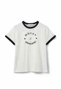 Camiseta blanca de algodón con cuello y mangas negras. Presenta un texto gráfico redondo: “HÔTEL de IMAGINÉ” con pequeños acentos de corazón.