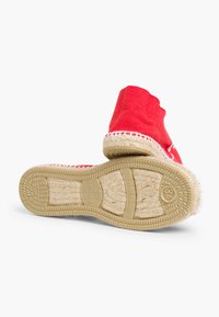 Espadrille en toile rouge avec un bout arrondi, détail en corde de jute sur la semelle et semelle en caoutchouc texturé. Caractéristiques d'un logo imprimé au bas.