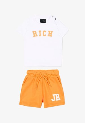 Chemise blanche à manches courtes avec le texte « RICH » associée à un short orange à cordon avec le texte « JR » sur la jambe.