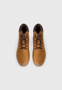 Botas de tobillo de cuero marrón con punta redonda, diseño de cordones, parte superior acolchada y suelas de goma marrón contrastantes. Presenta ojales metálicos para los cordones.