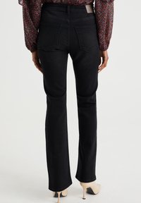 Jeans neri a zampa d'elefante con vita alta e due tasche posteriori, realizzati in tessuto denim. Presentano una texture liscia e dettagli di cuciture minime.