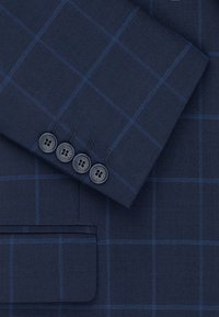 Marynarski niebieska marynarka w kratę z rękawami z czterema czarnymi guzikami, z kontrastującymi niebieskimi przeszyciami i teksturowanym wykończeniem materiału.