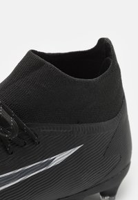 Scarpa da calcio nera con un design elegante, superficie testurizzata, logo prominente e un alto colletto elastico per supporto.