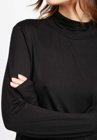 Top nero a maniche lunghe con collo alto e design aderente. Realizzato in tessuto morbido e elasticizzato. Presenta aperture per il pollice sui polsini.