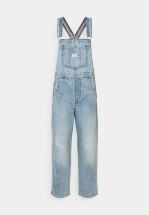 Denim overalls in light blue, featuring adjustable straps, a front pocket, and a distressed detail on the right leg. Loose-fitting design.