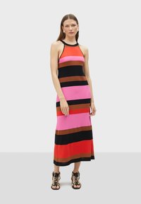 Knitted maxi dress featuring horizontal stripes in red, pink, brown, and black. Classic halter neck and slight stretch. Paired with black studded sandals.