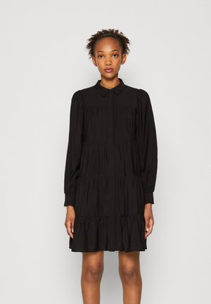 Black tiered dress made of lightweight fabric. Features long sleeves, a pointed collar, and button-down front. Flowy silhouette.