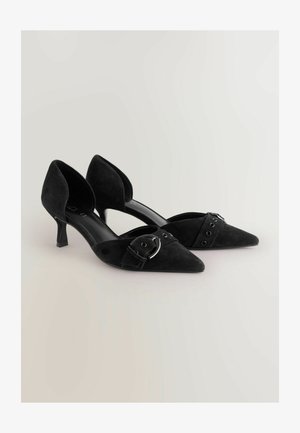 Czarne zamszowe buty na wysokim obcasie z szpiczastym noskiem, z regulowanym paskiem i metalowym zapięciem po bokach.