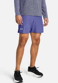 Lila idrottsshorts i lätt tyg, med elastisk midja och diskret logodetalj. Bärs med svarta idrottsskor.