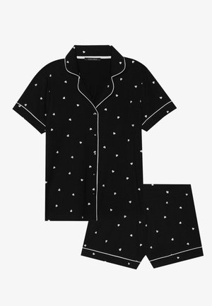 Black pajama set featuring short-sleeve top and shorts. White heart pattern with white piping along collar and shorts hem. Soft fabric.