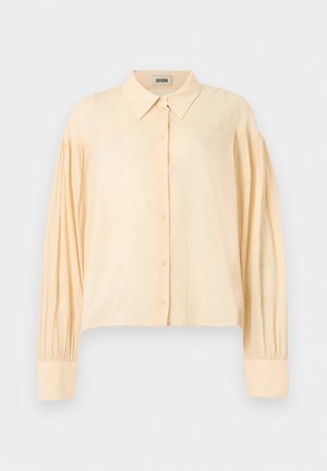 Chemise beige à manches longues avec boutons, col pointu et détails de tissu froncé aux épaules et aux poignets.