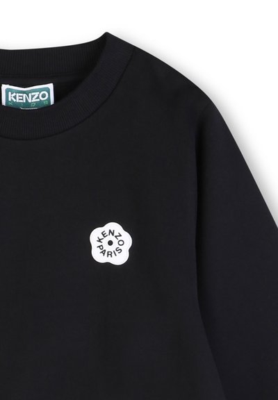 Sweat-shirt noir avec un logo rond blanc comportant l'inscription "KENZO PARIS". Encolure côtelée, texture douce, sans autres motifs ou accents visibles.