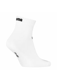 Weiße Knöchelsocke aus weichem Stoff, mit einem gerippten Bündchen. Schwarzes Puma-Logo nahe dem Bündchen und Größenangabe auf der Sohle.