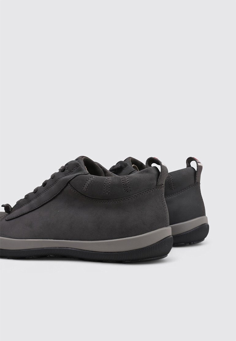 Black suede sneakers with a curved shape, minimalistic design, gray accents, and rubber soles. Features a pull tab at the heel.