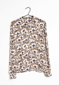 Blus med långa ärmar i mjukt tyg med en brun bakgrund och stora lila och vita blommönster. Rund halsringning och rak fåll.