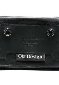 Bolsa de cuero negro con herrajes plateados, presenta una marca en relieve y una superficie texturizada. Incluye un detalle circular con ojales.