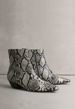 Knöchelhohe Stiefel aus Schlangenhaut mit spitzer Zehenpartie und niedrigem Blockabsatz, mit einem schwarz-weißen, strukturierten Muster und seitlichem Reißverschluss.